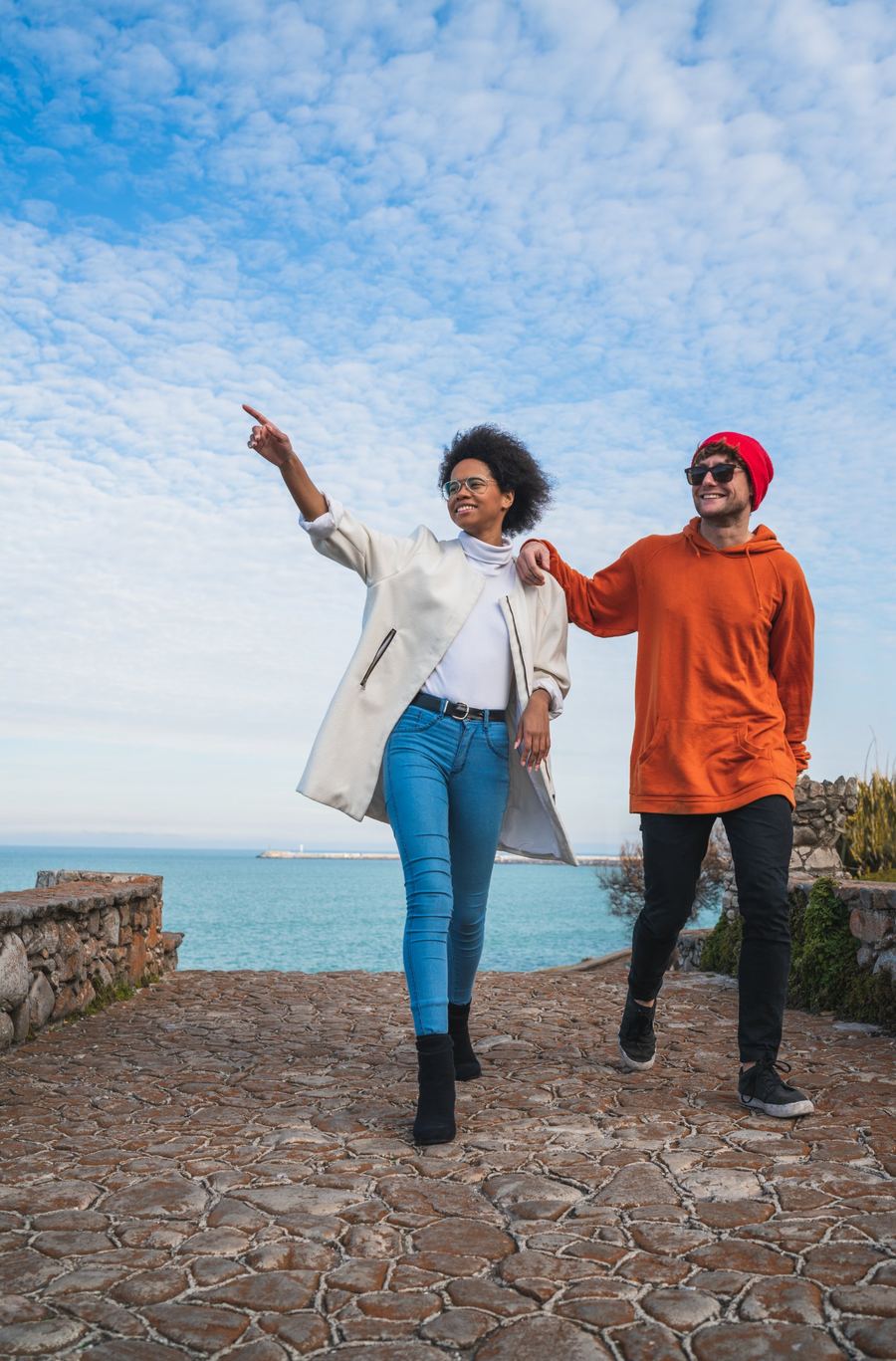Two friends exploring a coastal viewpoint and pointing at the horizon
