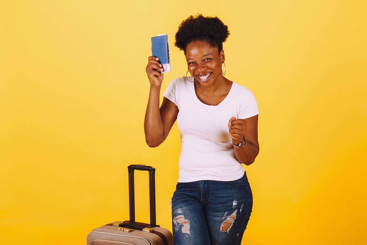 Smiling traveller holding a passport beside a suitcase